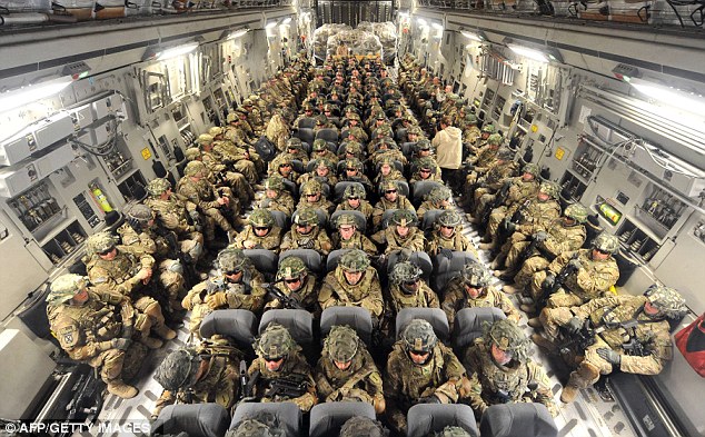 Close contact: US soldiers sit in rows of five with more colleagues lining the side of the plane as they travel 'cattle class' from Kyrgyzstan to Afghanistan